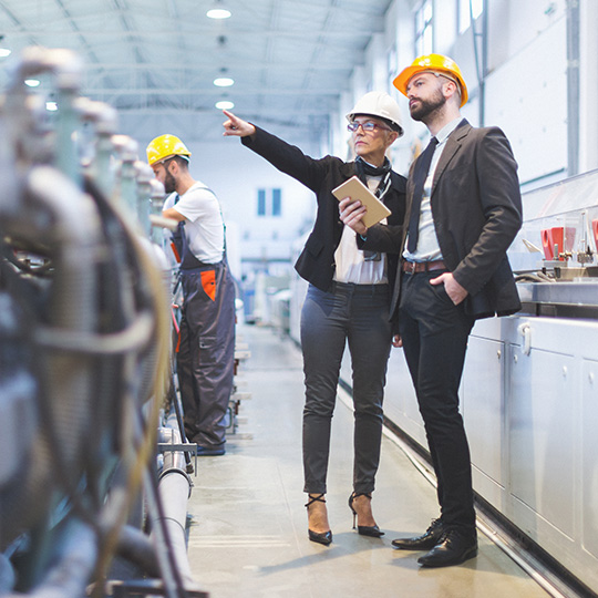 businessman and woman wearing hard hats on site